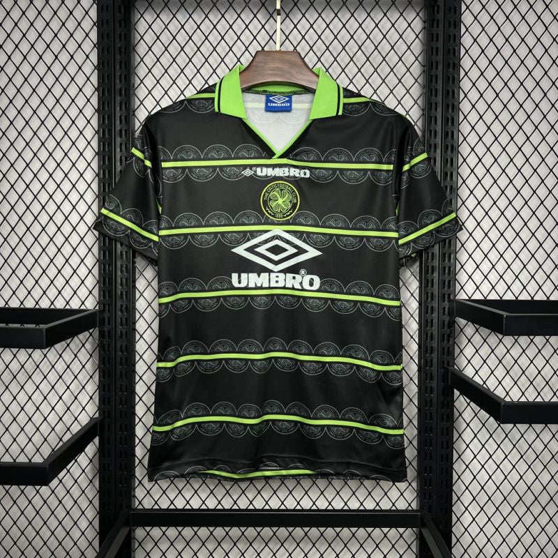 Celtic FC retro-style football shirt by Umbro with green and black horizontal patterns, hanging on a display rack.