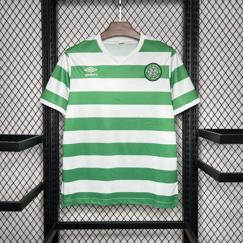 Celtic FC 1980 green and white hooped Umbro football shirt hanging on a wooden hanger against a mesh background