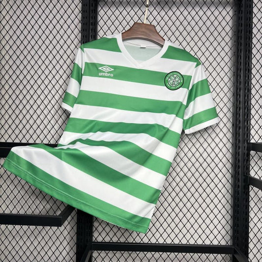 Celtic FC 1980 green and white hooped Umbro football shirt hanging on a wooden hanger against a mesh background