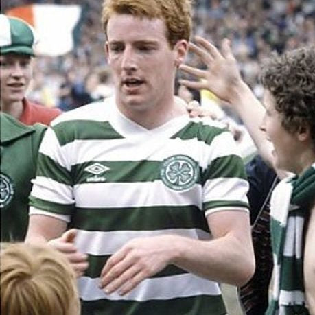 Celtic FC player wearing a green and white hooped Umbro football shirt in a crowded stadium scene