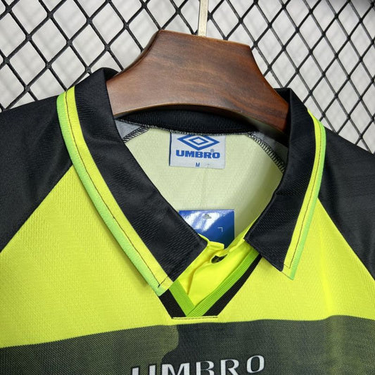 Close-up of the collar and Umbro label on a vintage Celtic F.C. yellow and dark green striped football shirt.