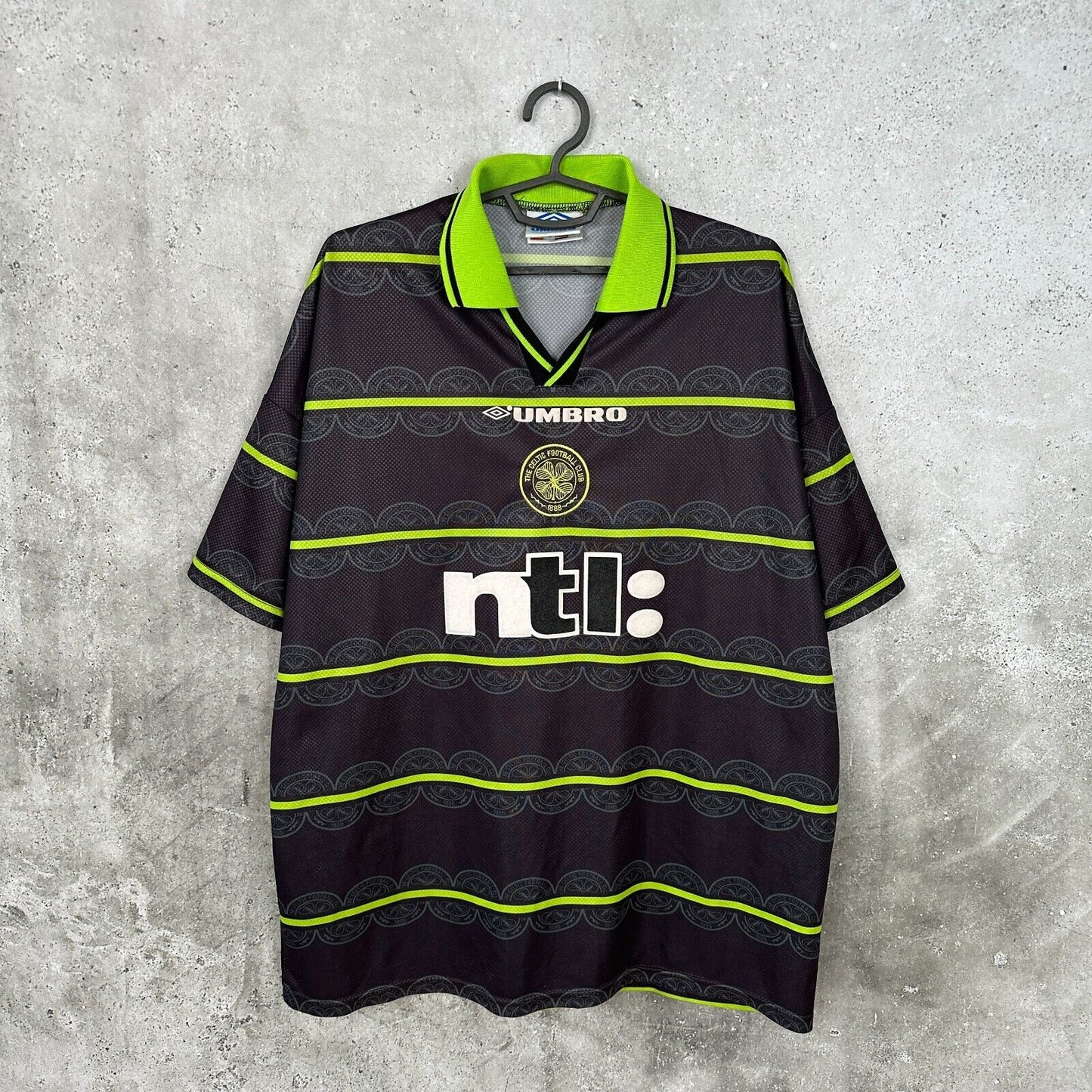 1999 Celtic FC football shirt featuring the Umbro logo, club crest, and neon yellow horizontal stripes on a dark background.