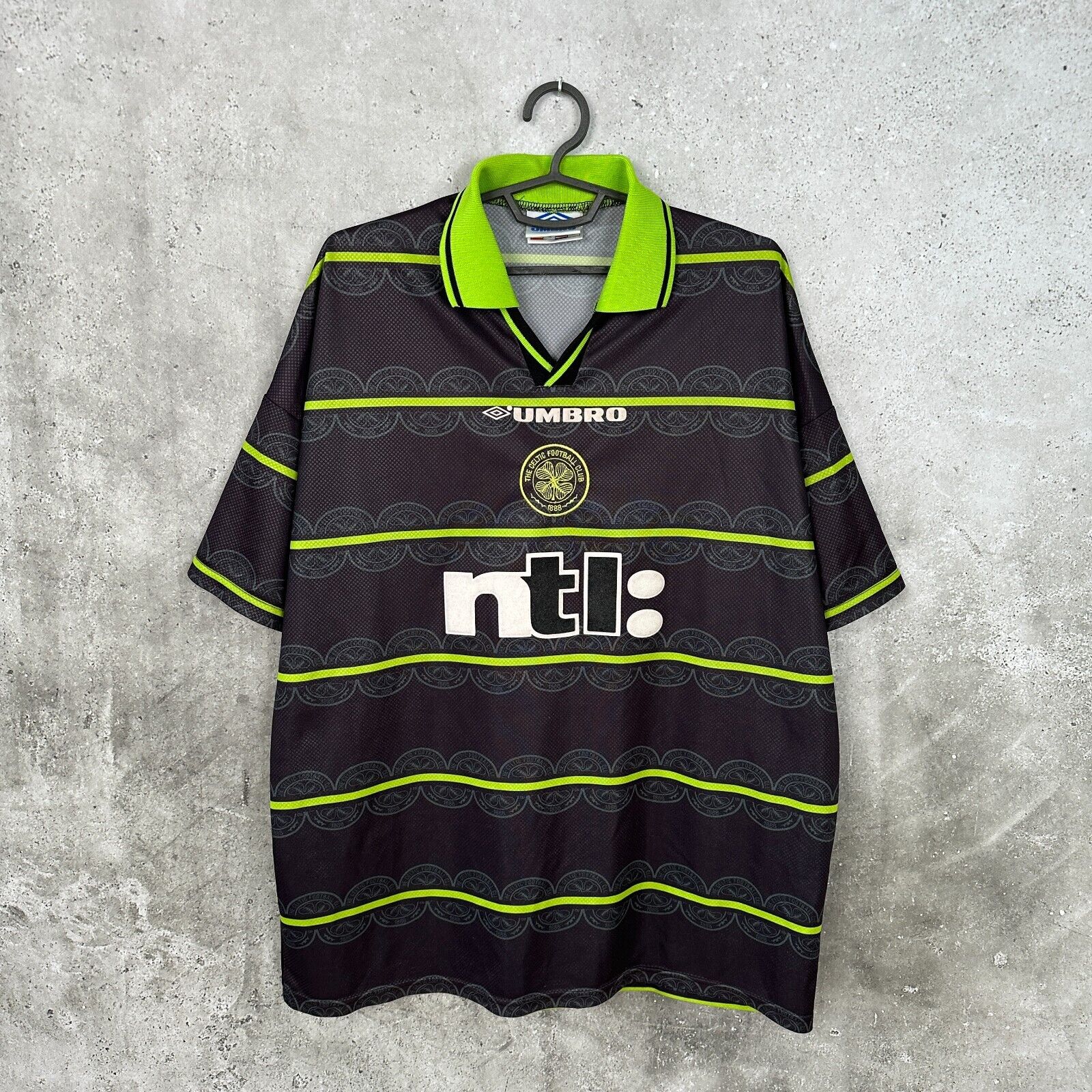 1999 Celtic FC football shirt featuring the Umbro logo, club crest, and neon yellow horizontal stripes on a dark background.